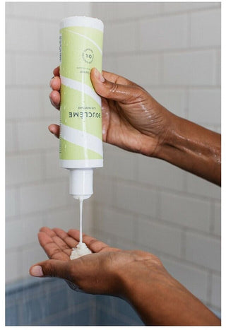 Mains versant la creme lavante Boucleme Curl Cleanser sous la douche, texture blanche onctueuse