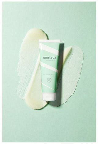 Tube Boucleme Scalp Exfoliating Shampoo pose sur fond vert menthe avec traces de texture exfoliante