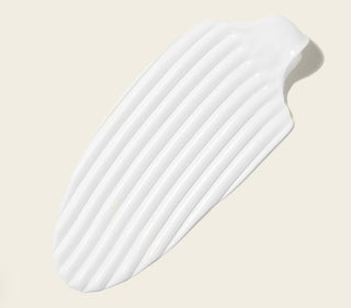 Texture creme blanche epaisse et striee du Boucleme Curl Cream sur fond beige