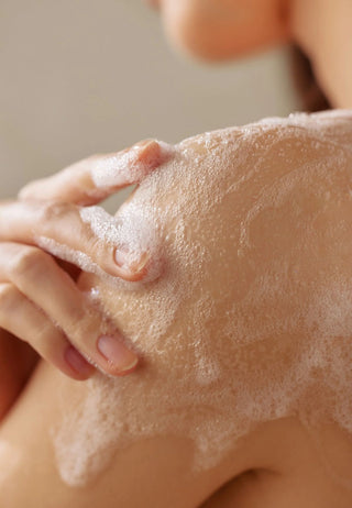 Gros plan mousse dense appliquée sur l'épaule, massage du nettoyant corps SOME BY MI AHA BHA PHA