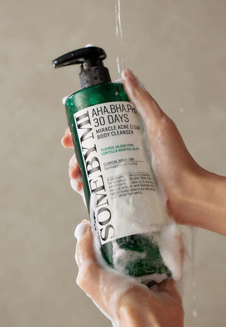 Mains savonneuses tenant le flacon SOME BY MI AHA BHA PHA nettoyant corps sous l'eau de la douche