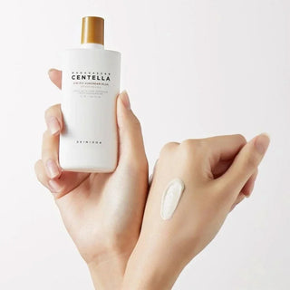 SKIN1004 Centella Suncream Plus tenue en main avec swatch de texture cremeuse blanche sur le dos de la main