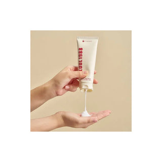 Mains pressant le tube K-SECRET Seoul 1988 Snail Mucin 93% pour déposer la crème dans la paume