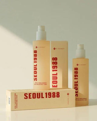 Deux flacons et boite KSECRET Seoul 1988 Essence Snail Mucin poses sur un coffret beige