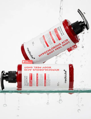 Deux flacons MEDICUBE Body Peel Shot couches sous des eclaboussures d'eau sur tablette en verre