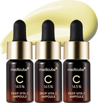Trois flacons Medicube Deep Vita C Ampoule 2.0 alignes avec trace de serum jaune en arriere-plan