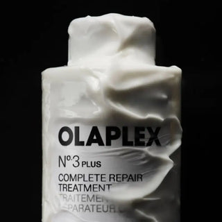 Texture crème blanche onctueuse recouvrant le flacon OLAPLEX No.3 Plus sur fond noir - swatch