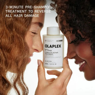 Deux femmes souriantes tenant le soin OLAPLEX No.3 Plus - traitement pré-shampoing réparateur de 3 minutes