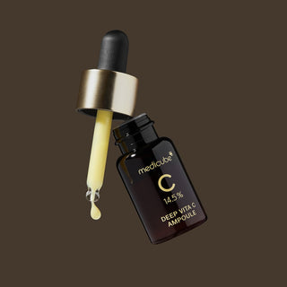 Medicube Deep Vita C Ampoule flacon brun et pipette doree en suspension sur fond brun fonce