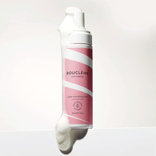 Boucleme Super Volumising Foam - flacon rose incline avec mousse blanche debordante sur fond clair