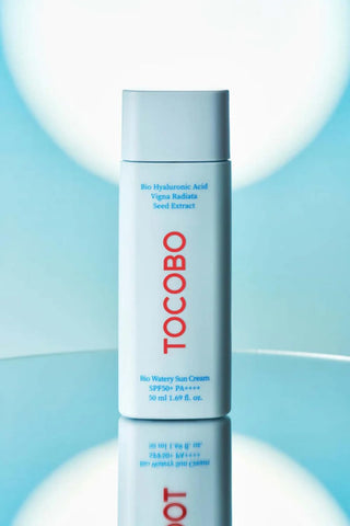 TOCOBO Bio Watery Sun Cream 50ml sur surface reflechissante avec eclairage bleu et blanc