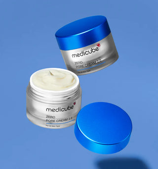 Deux pots Medicube Zero Pore Cream 2.0 ouverts et couvercle bleu flottant sur fond bleu lavande