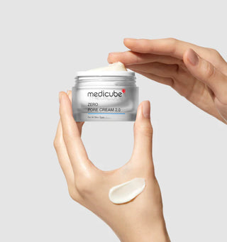 Main tenant le pot ouvert Medicube Zero Pore Cream 2.0 avec swatch de creme blanche sur le dos de la main