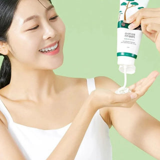 Round Lab Nettoyant Pin Cica - mannequin versant la creme dans sa paume sur fond vert