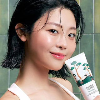 Round Lab Nettoyant Pin Cica - mannequin tenant le tube pres de son visage dans salle de bain verte