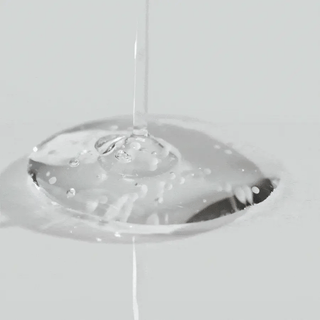 Goutte de sérum transparent SKIN1004 Centella Ampoule versée sur une surface lisse avec bulles visibles