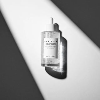 Flacon SKIN1004 Centella Ampoule vu de dessus sur fond bicolore gris et blanc avec ombre portée