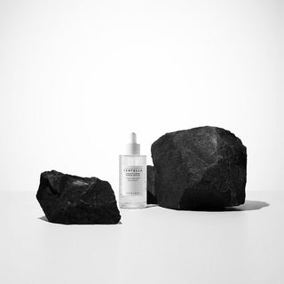 SKIN1004 Centella Tone Brightening Ampoule posée entre deux pierres noires sur fond blanc minimaliste