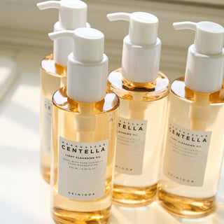 Plusieurs flacons pompe SKIN1004 Centella Light Cleansing Oil 200ml alignes en lumiere naturelle doree