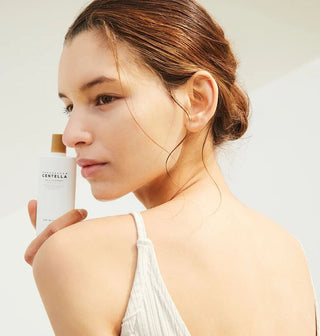 Mannequin tenant le tube SKIN1004 Centella Suncream Plus pres du visage, peau lumineuse et hydratee