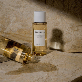Deux flacons SKIN1004 Centella Toning Toner poses sur pierres naturelles beiges avec jeux de lumiere